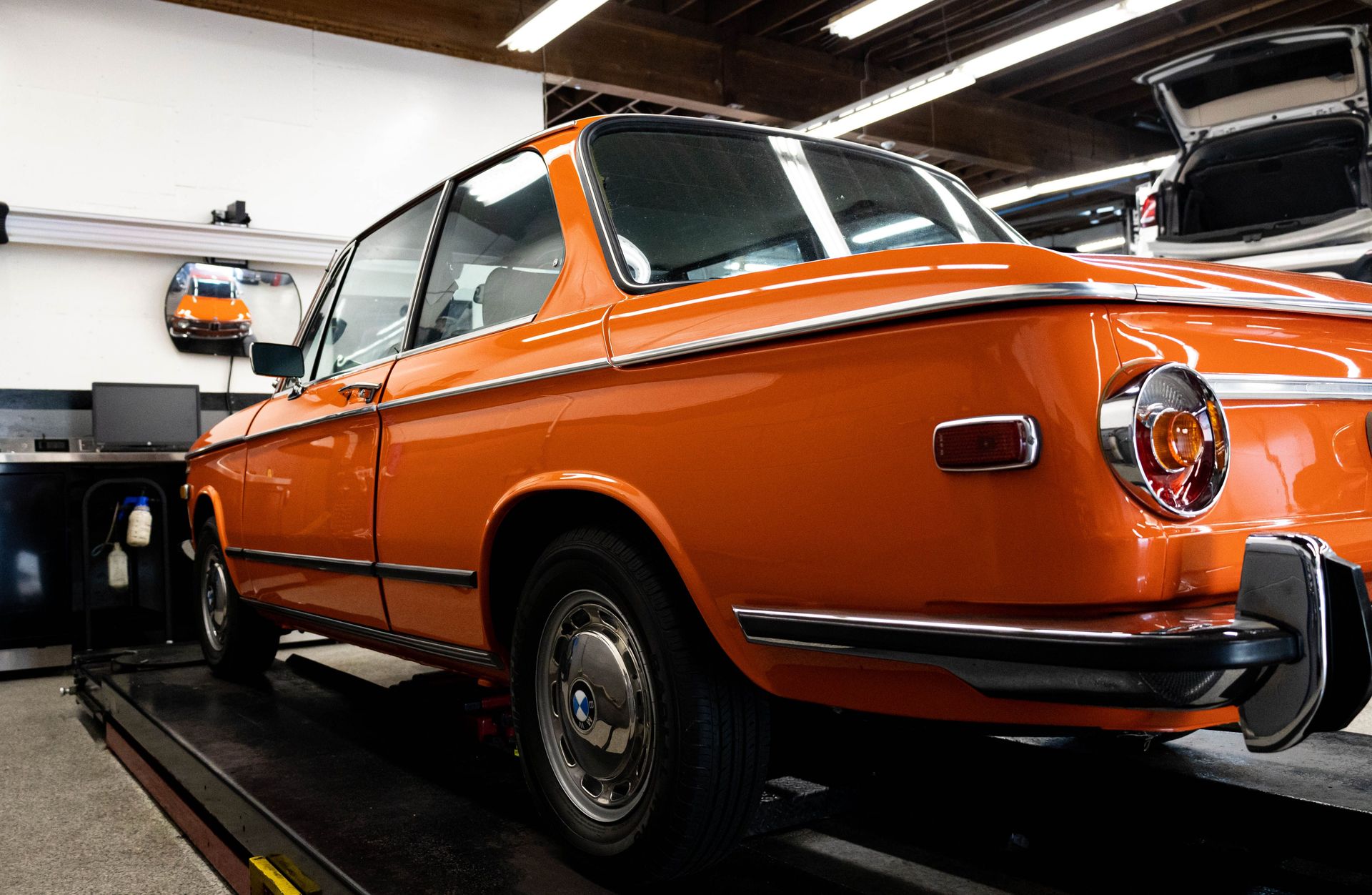 Classic bright orange BMW car parked in auto workshop. Perfect for automotive enthusiasts.